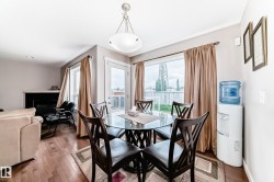 Dining area with wood-finish flooring and a contemporary chandelier - 