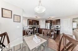 Open-concept kitchen featuring dark wood cabinetry, stainless steel appliances, a center island with seating, and wood-finish flooring - 
