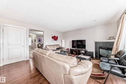 Living area featuring wood-finish flooring, a contemporary fireplace with a dark tile surround, light-toned walls, and recessed lighting - 2808 36 Avenue, Edmonton, AB 