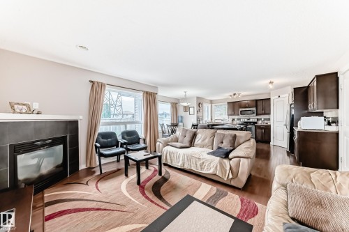 Spacious living area featuring wood-finish flooring, a tiled fireplace with a white mantel, and ample natural light from large windows - 2808 36 Avenue, Edmonton, AB 