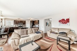 Open-concept living space featuring wood-finish flooring, recessed lighting, and a kitchen with dark cabinetry and stainless steel appliances - 