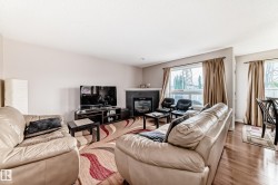 Living area featuring a fireplace with a dark surround and mantle, hardwood flooring, and multiple large windows with drapes - 