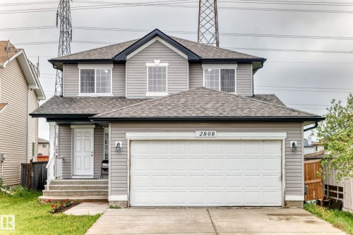 Two-story residence featuring light gray siding, a two-car garage, and a covered front entry - 2808 36 Avenue, Edmonton, AB 