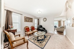 Carpeted living area featuring multiple windows with blinds, a circular semi-flush mount ceiling light, and light-toned walls - 