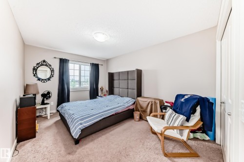 Carpeted bedroom featuring a large window with privacy coverings, a built-in closet with a white panel door, and a flush-mount ceiling light fixture - 2808 36 Avenue, Edmonton, AB 