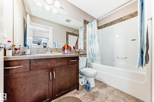 Bathroom featuring a spacious vanity with an integrated sink, dark wood-finish cabinetry, and a full-width mirror - 2808 36 Avenue, Edmonton, AB 