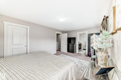 Spacious bedroom featuring light neutral wall tones, textured carpeting, and a built-in overhead light fixture - 