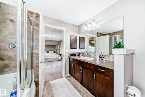 Bathroom featuring a single vanity with dark wood-finish cabinetry, a white basin, and a large wall-mounted mirror - 2808 36 Avenue, Edmonton, AB 