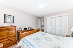 Bedroom featuring neutral-toned walls, white bi-fold closet doors with trim, a ceiling-mounted light fixture, and light-colored flooring - 