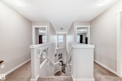 Upper-level hallway with neutral wall paint and carpeting - 