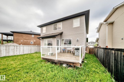 Rear exterior featuring a wood deck with glass panel railing, grey siding, and a fenced yard - 2808 36 Avenue, Edmonton, AB 