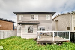Rear exterior featuring light-toned horizontal siding and a dark shingled roof - 