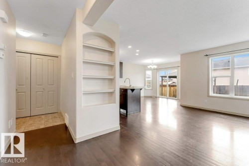 Expansive open-concept living area featuring wood-finish flooring, abundant natural light from multiple windows, and a sliding glass door leading to the exterior - 16315 55 Street, Edmonton, AB 