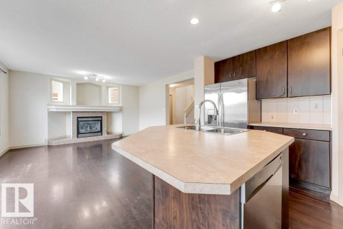 Kitchen island featuring a double-basin sink and integrated stainless-steel dishwasher - 16315 55 Street, Edmonton, AB 