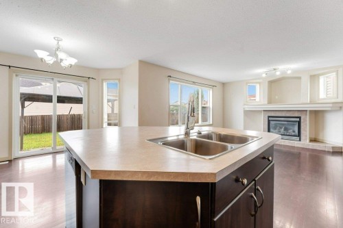 Kitchen island with double stainless steel sink and light-toned countertop - 16315 55 Street, Edmonton, AB 