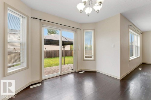 Open concept room featuring dark wood-finish flooring, light neutral walls, and a multi-light chandelier - 16315 55 Street, Edmonton, AB 