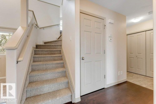 Carpeted staircase with light-toned walls and a white paneled door - 16315 55 Street, Edmonton, AB 