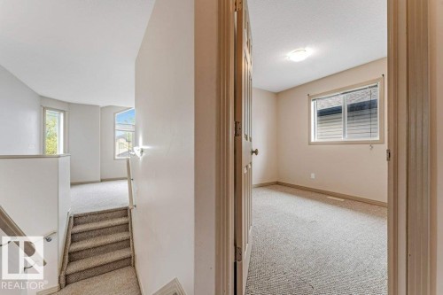 Upper level featuring neutral carpeting, a staircase with a wooden handrail, and multiple windows providing natural light - 16315 55 Street, Edmonton, AB 