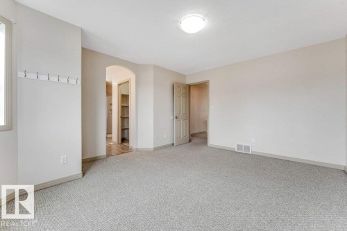Spacious room featuring light-toned walls, grey carpet flooring, and a large window providing natural light - 16315 55 Street, Edmonton, AB 