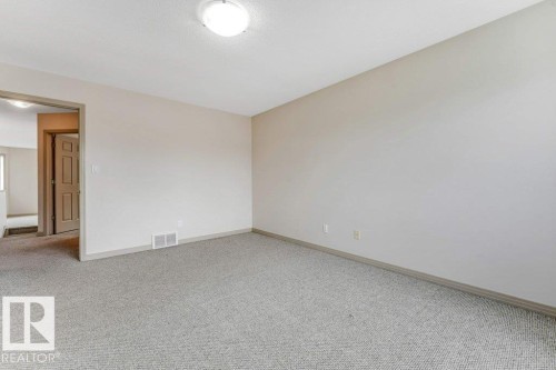 Spacious room featuring neutral carpeting and light-colored walls, complemented by a flush-mount ceiling light - 16315 55 Street, Edmonton, AB 