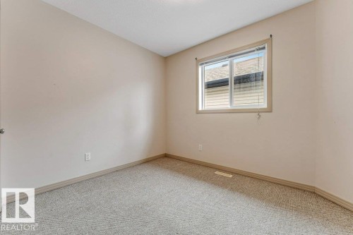 Room featuring light neutral-toned walls, a large window with blinds, and light-colored carpeting - 16315 55 Street, Edmonton, AB 