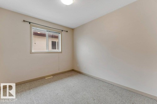 Carpeted room featuring a window with horizontal blinds, light-toned walls, baseboard molding, and a ceiling-mounted light fixture - 16315 55 Street, Edmonton, AB 