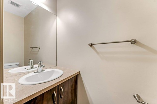Bathroom vanity featuring an oval undermount sink with a chrome faucet, set into a light-toned countertop - 16315 55 Street, Edmonton, AB 