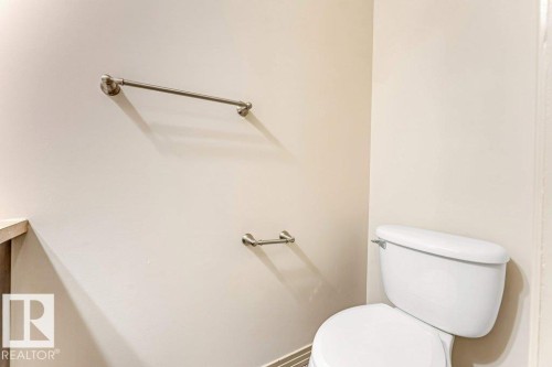 Bathroom featuring a white toilet, light-toned walls, and brushed nickel hardware including a towel bar - 16315 55 Street, Edmonton, AB 