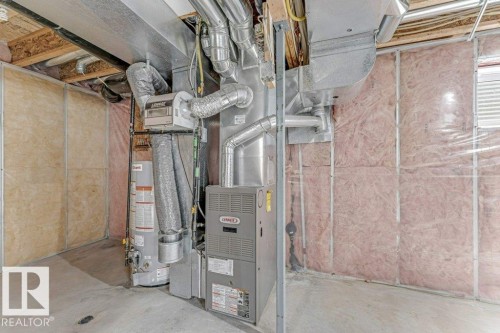 Utility area featuring a Lennox furnace, hot water heater, exposed ductwork, concrete flooring, and insulated walls - 16315 55 Street, Edmonton, AB 