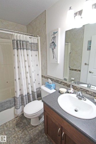 Full bathroom featuring a single vanity with a dark countertop, white oval sink, and chrome faucet - 334 7001 Northview Drive, Wetaskiwin, AB - Indoor Photo Showing Bathroom