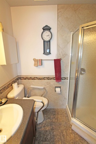 Bathroom featuring a glass-enclosed shower, vanity with an integrated sink, mosaic tile accents, and tiled flooring - 334 7001 Northview Drive, Wetaskiwin, AB - Indoor Photo Showing Bathroom