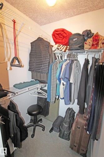 Walk-in closet featuring built-in wire shelving, hanging rods, light gray walls, textured ceiling, and carpet flooring - 334 7001 Northview Drive, Wetaskiwin, AB - Indoor With Storage