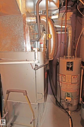 Utility area featuring a water heater and furnace with exposed ductwork and piping - 334 7001 Northview Drive, Wetaskiwin, AB - Indoor Photo Showing Basement