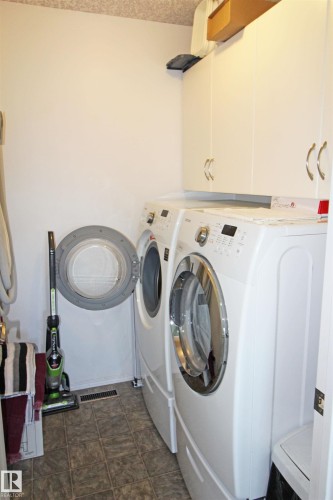 Dedicated laundry area featuring tile flooring and built-in white cabinetry - 334 7001 Northview Drive, Wetaskiwin, AB - Indoor Photo Showing Laundry Room
