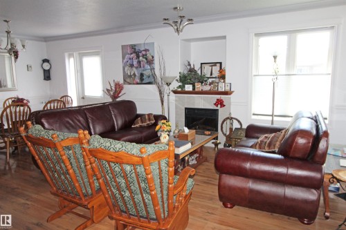 Spacious living area featuring wood-finish flooring, crown molding, and a fireplace with a tile surround and wood mantel - 334 7001 Northview Drive, Wetaskiwin, AB - Indoor With Fireplace
