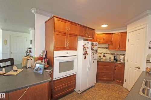 Kitchen with rich wood cabinetry and dark countertops - 334 7001 Northview Drive, Wetaskiwin, AB - Indoor Photo Showing Kitchen With Double Sink