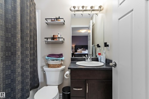 Bathroom featuring a dark wood-finish vanity with a white oval sink, dark countertop, and brushed nickel hardware - 6822 Cardinal Link, Edmonton, AB 