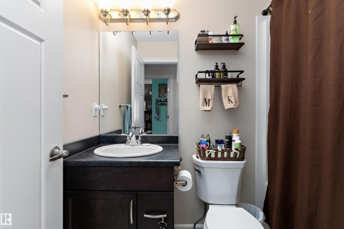 Bathroom featuring a vanity with a dark countertop, an integrated sink, and dark wood cabinetry - 6822 Cardinal Link, Edmonton, AB 