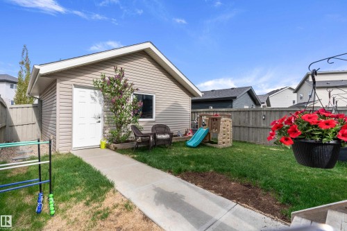 Detached garage with siding exterior and gabled roofline, complemented by a concrete pathway and a wooden fence - 6822 Cardinal Link, Edmonton, AB 