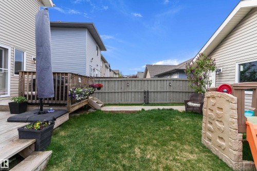Expansive backyard featuring a manicured lawn, a full wooden privacy fence, and a multi-level wood deck - 6822 Cardinal Link, Edmonton, AB 