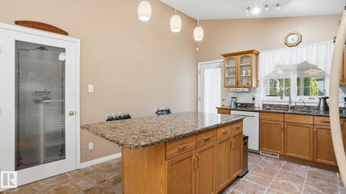 Kitchen featuring a granite-look island with integrated storage, wood cabinetry, and a double-basin sink - 856 Graham Wynd, Edmonton, AB 
