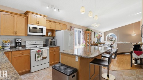 Kitchen featuring wood cabinetry, a built-in microwave, and a stone-finish countertop - 856 Graham Wynd, Edmonton, AB 
