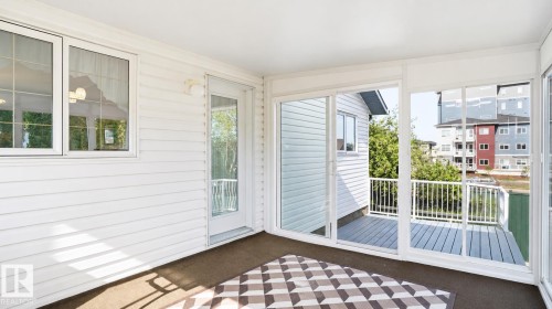 Enclosed sunroom featuring multiple windows and sliding glass doors opening to an outdoor deck - 856 Graham Wynd, Edmonton, AB 