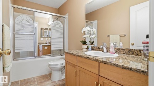 Bathroom featuring a built-in vanity with a granite countertop, undermount sink, and wood-finish cabinetry - 856 Graham Wynd, Edmonton, AB 