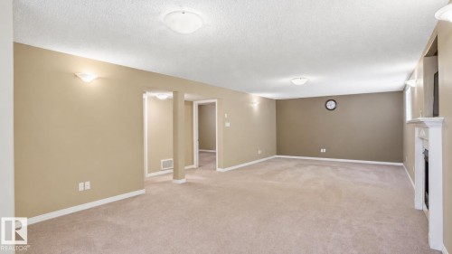 Spacious carpeted room featuring a white mantelpiece, recessed wall lighting, and multiple entryways - 856 Graham Wynd, Edmonton, AB 