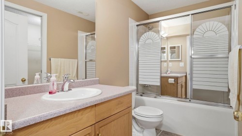 Bathroom featuring a vanity with an integrated sink, a light-toned countertop, and wood-finish cabinetry - 856 Graham Wynd, Edmonton, AB 
