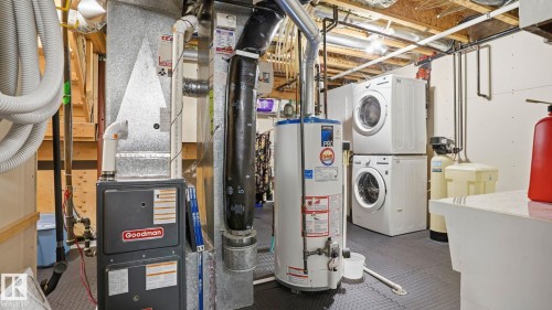 Dedicated utility area featuring a water heater, furnace, stackable washer and dryer units, and a utility sink - 856 Graham Wynd, Edmonton, AB 