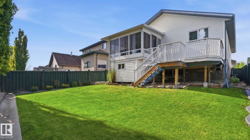 Expansive rear yard featuring a screened-in porch, large outdoor deck with stairs, a manicured lawn, and a perimeter fence - 856 Graham Wynd, Edmonton, AB 