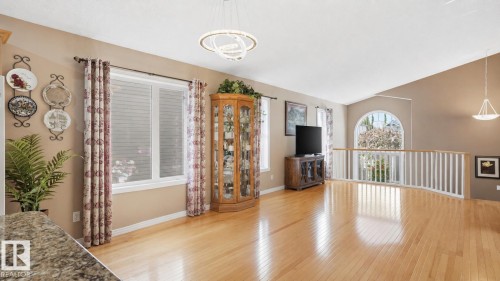 Spacious interior featuring wood-finish flooring, a vaulted ceiling, and an arched window - 856 Graham Wynd, Edmonton, AB 