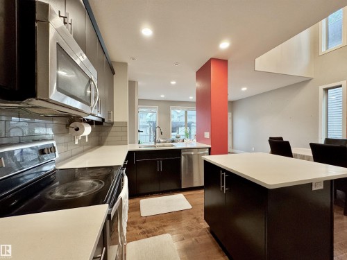 Contemporary kitchen featuring dark wood cabinetry, stainless steel appliances, light countertops, and subway tile backsplash - 3254 Allan Way, Edmonton, AB 